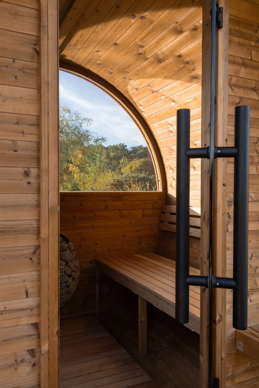 The black door handle against the timber interior, with the half-round window behind it